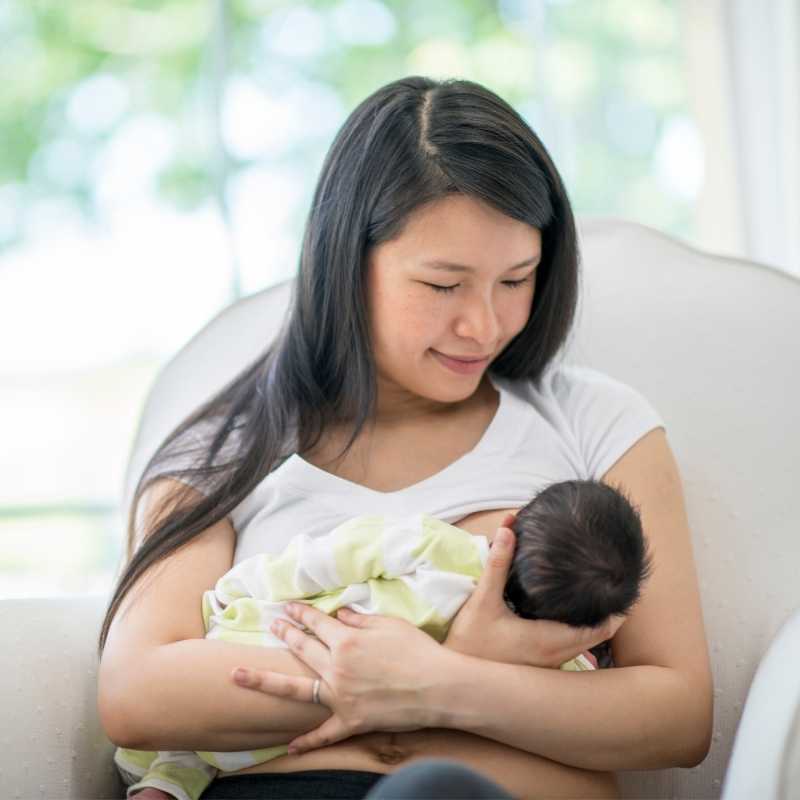 Mamãe asiática amamentando o seu bebê