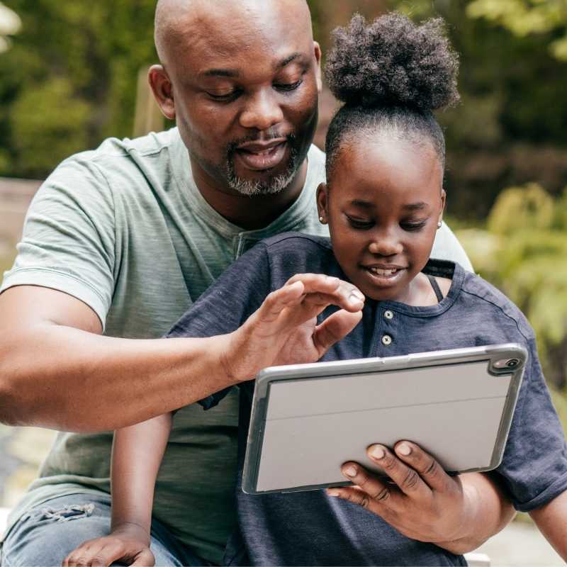 Pai negro ensigando sua filha sobre o uso de tecnologia
